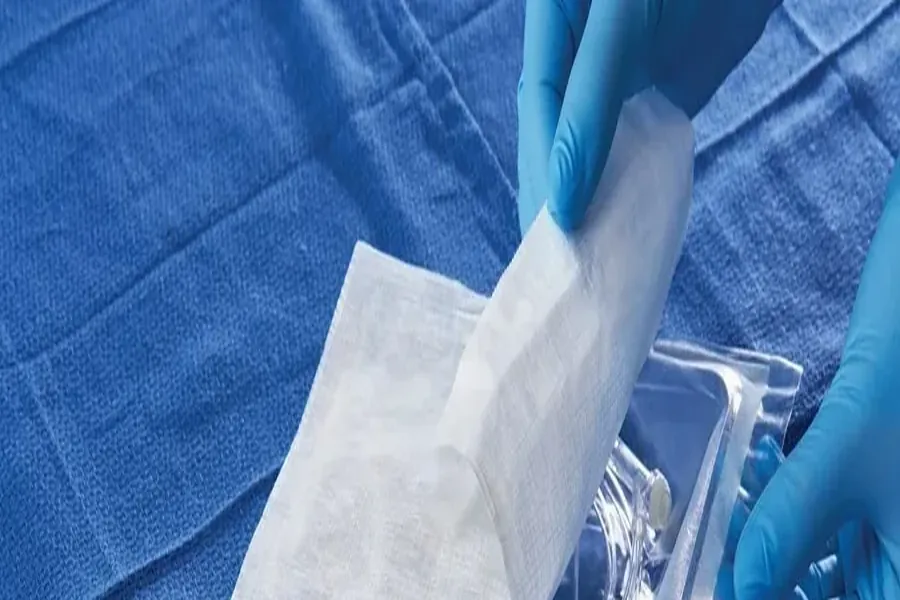 Gloved hands opening sterile flexible packaging containing a medical device